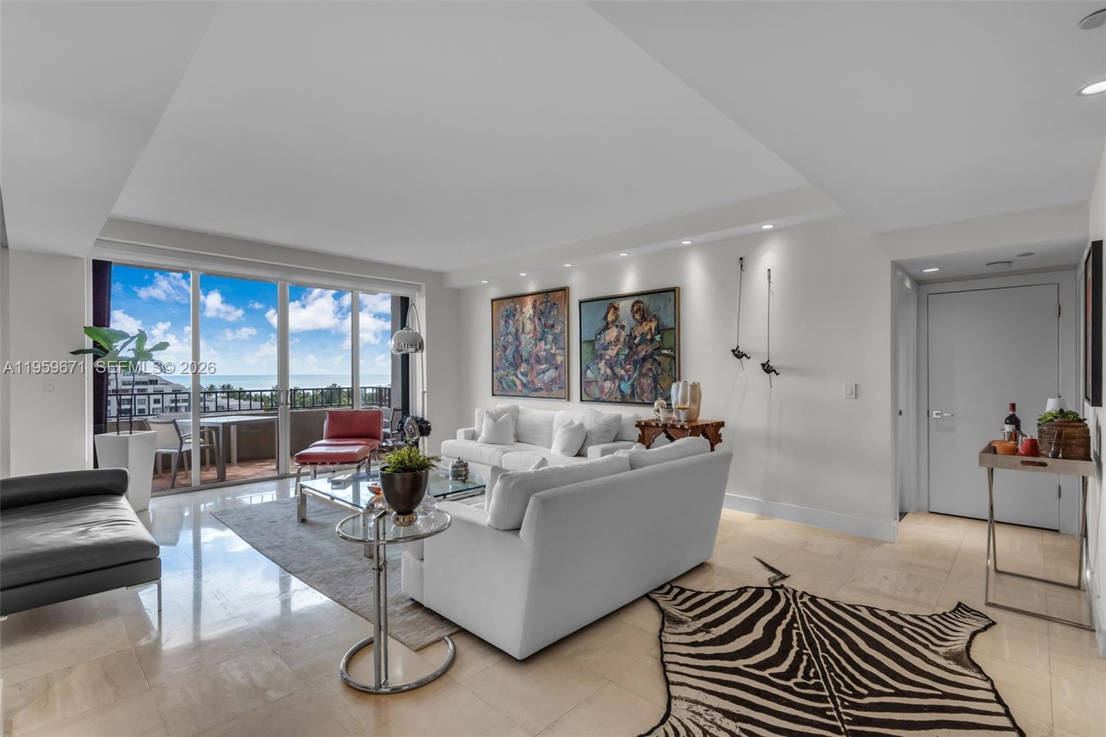 A bright living room features white sofas, a zebra-print rug, and a balcony with ocean views — 151 Crandon Blvd # 802, Key Biscayne FL 33149, KEY BISCAYNE, FL