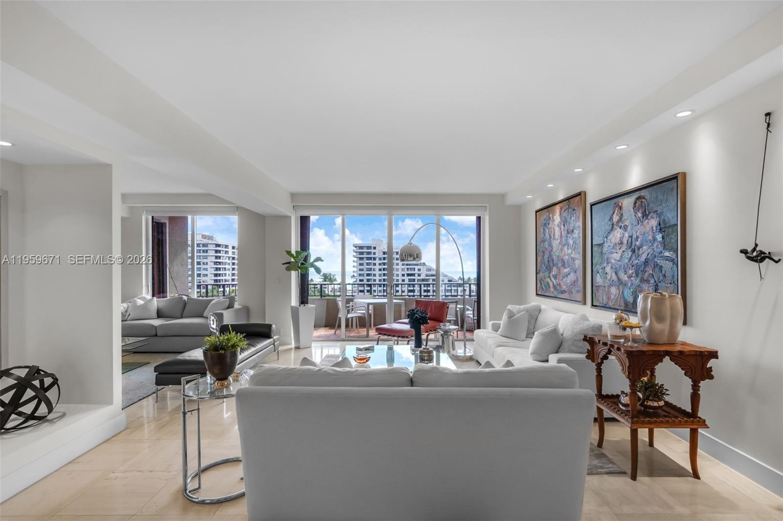A bright living room features white sofas, large abstract paintings, and a balcony with ocean views — 151 Crandon Blvd # 802, Key Biscayne FL 33149, KEY BISCAYNE, FL