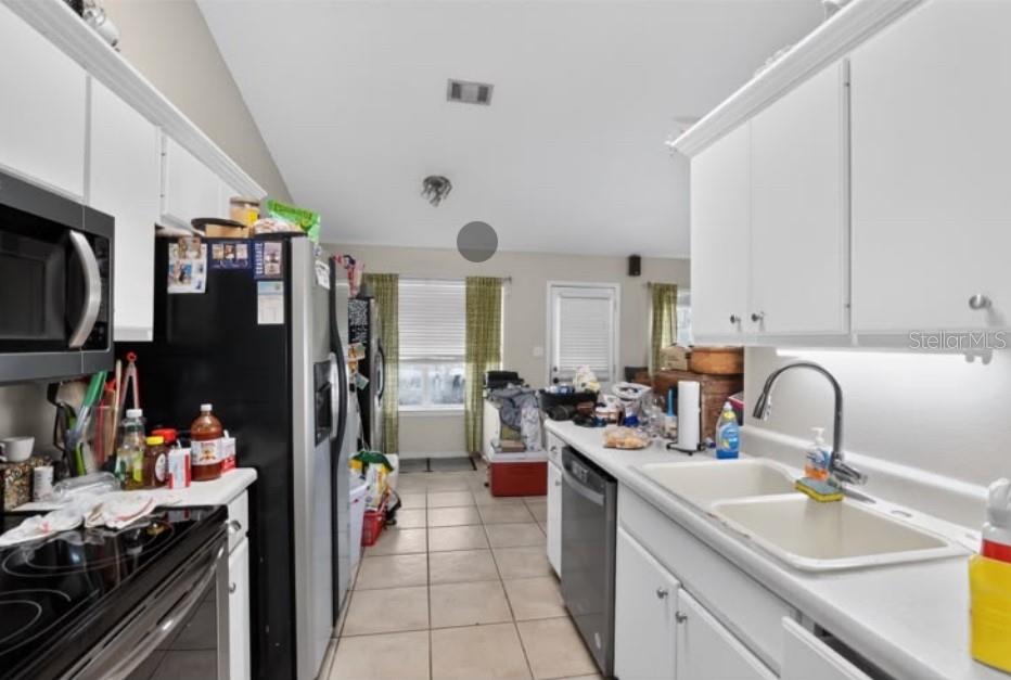 A galley-style kitchen features white cabinets, stainless steel appliances, and light-colored tile flooring — 4374 MARILYN COURT, GULF BREEZE, FL