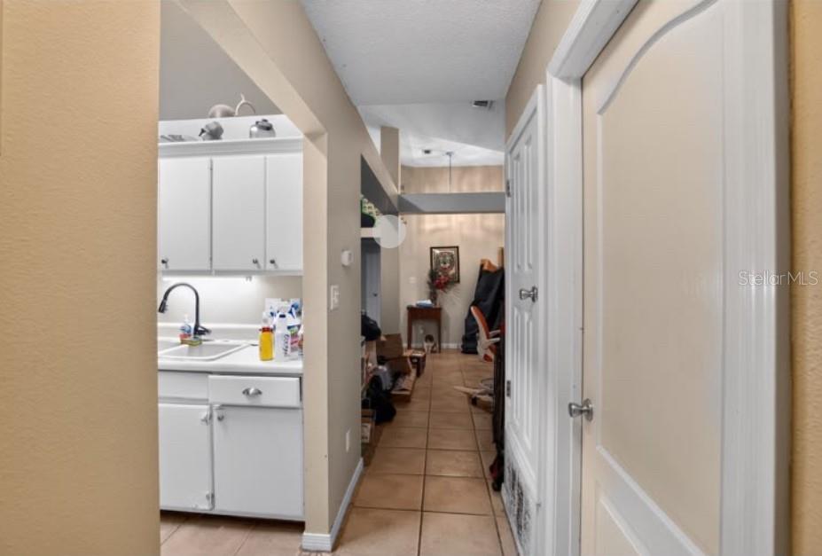 A hallway leads past a kitchen with white cabinets toward a room with tiled floors — 4374 MARILYN COURT, GULF BREEZE, FL