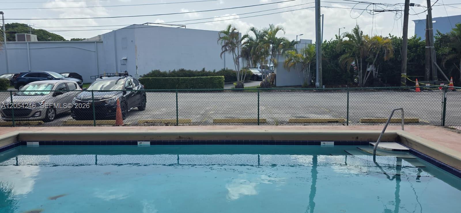 A swimming pool is in the foreground with a parking lot and building behind it — 7901 SW 64th Ave # 4, South Miami FL 33143, SOUTH MIAMI, FL