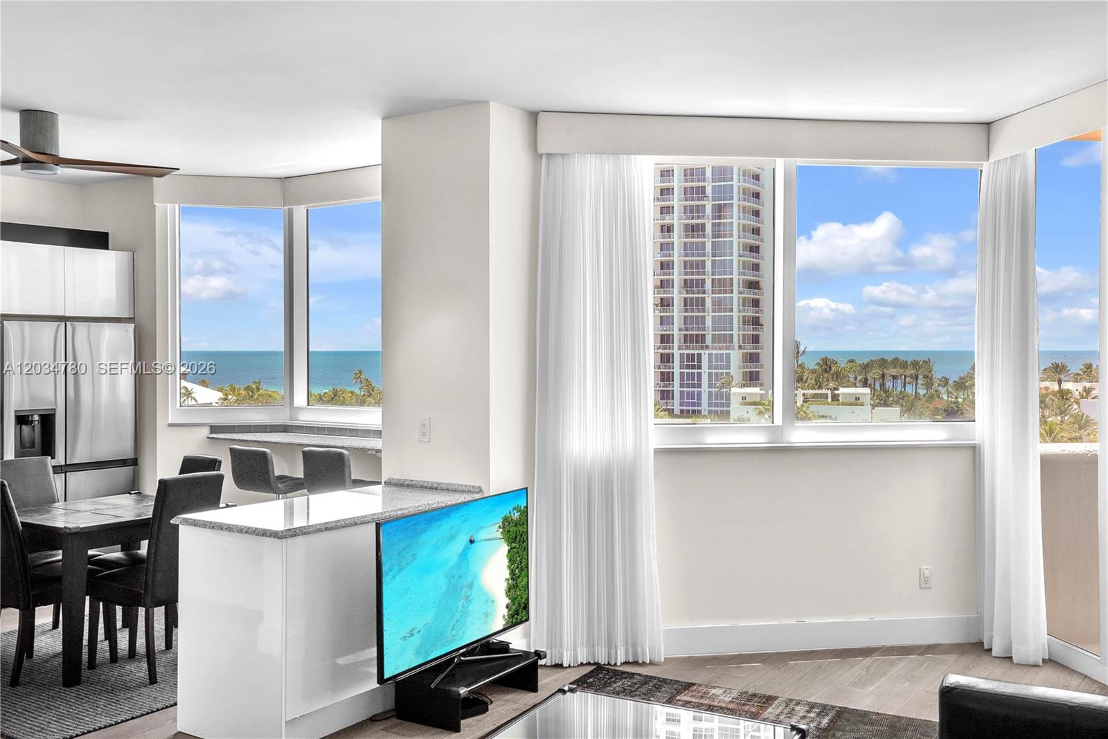 A modern living area features a kitchen island, dining space, and floor-to-ceiling ocean view windows — 300 S POINTE DR # 809, Miami Beach FL 33139, MIAMI BEACH, FL