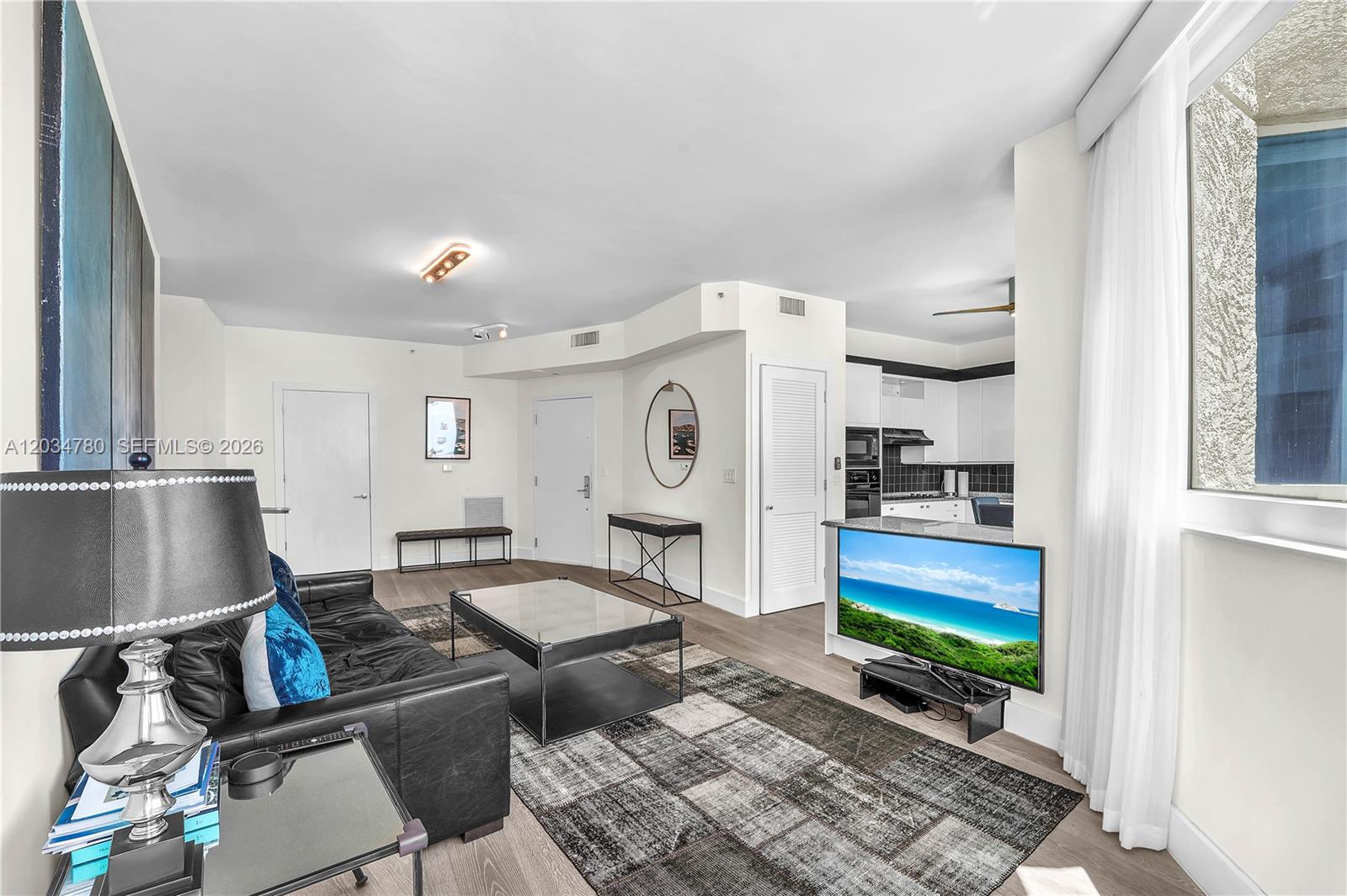 A living room features a black leather sofa, a glass coffee table, and an open kitchen — 300 S POINTE DR # 809, Miami Beach FL 33139, MIAMI BEACH, FL