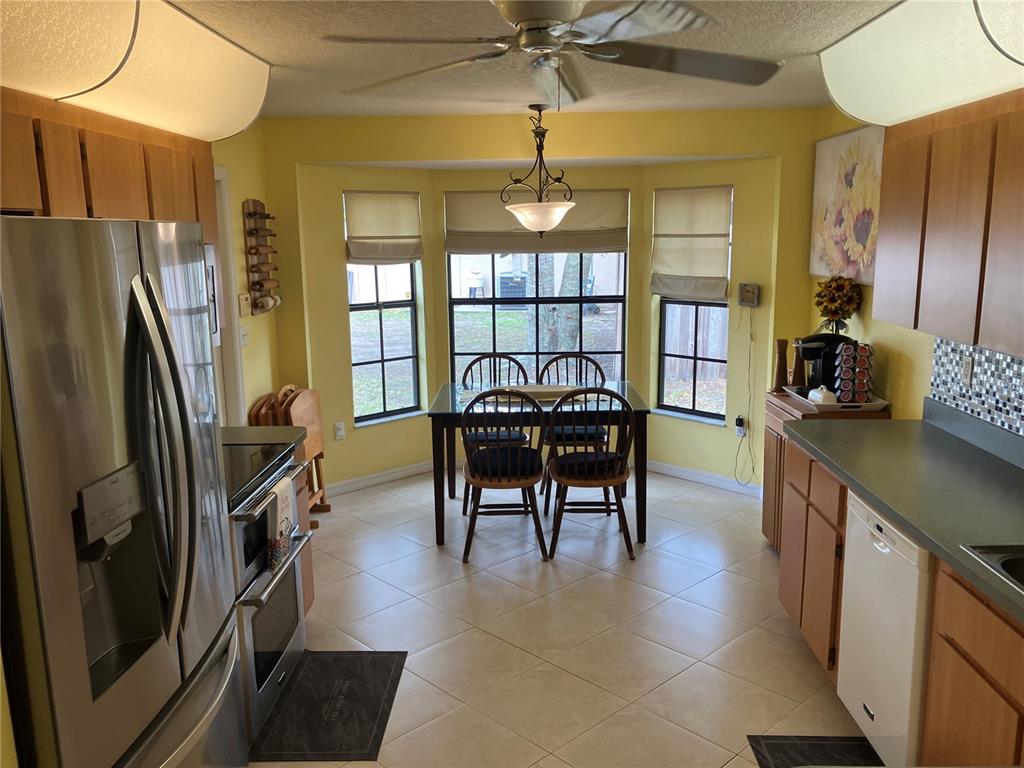 A kitchen with light wood cabinets, stainless steel appliances, and a dining area with windows — 14050 BRIGHTON STREET, SPRING HILL, FL