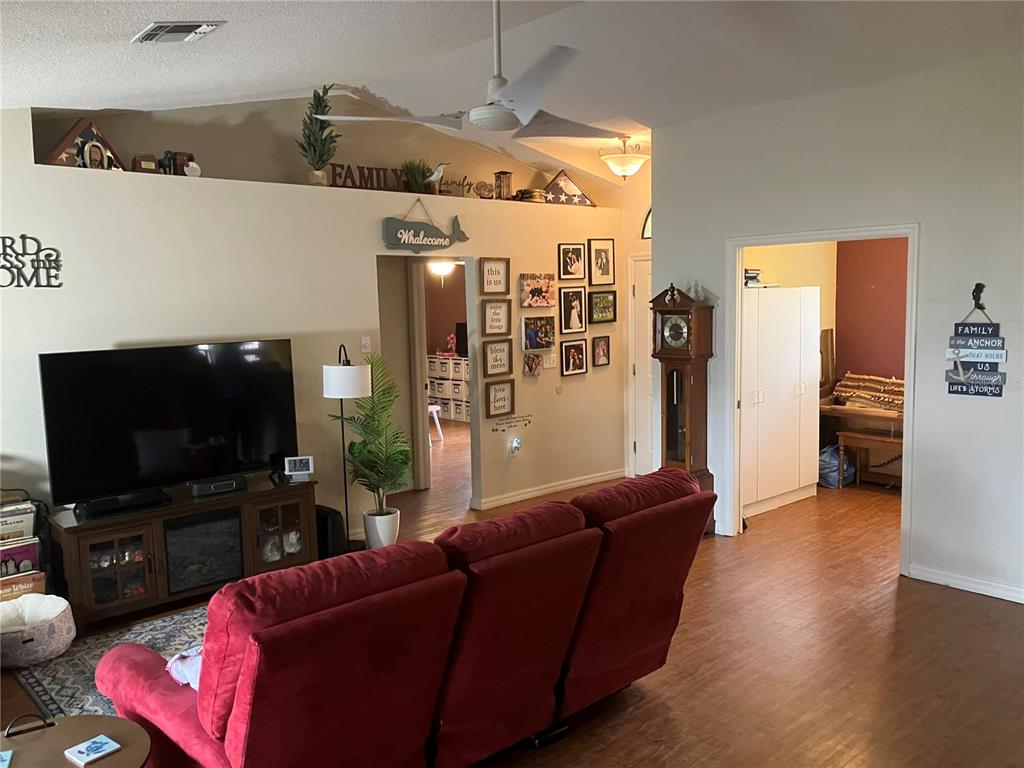 A living room features a red reclining sofa, a television on a console, and a grandfather clock — 14050 BRIGHTON STREET, SPRING HILL, FL