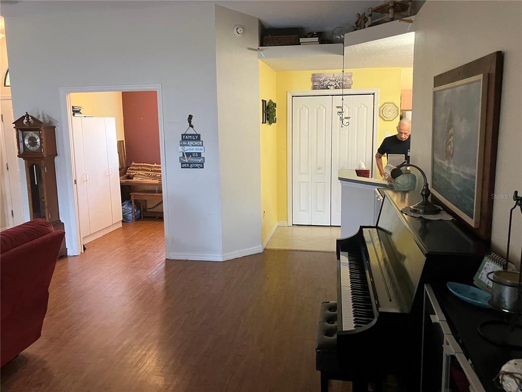 A living room features a piano, a grandfather clock, and a view into a hallway — 14050 BRIGHTON STREET, SPRING HILL, FL