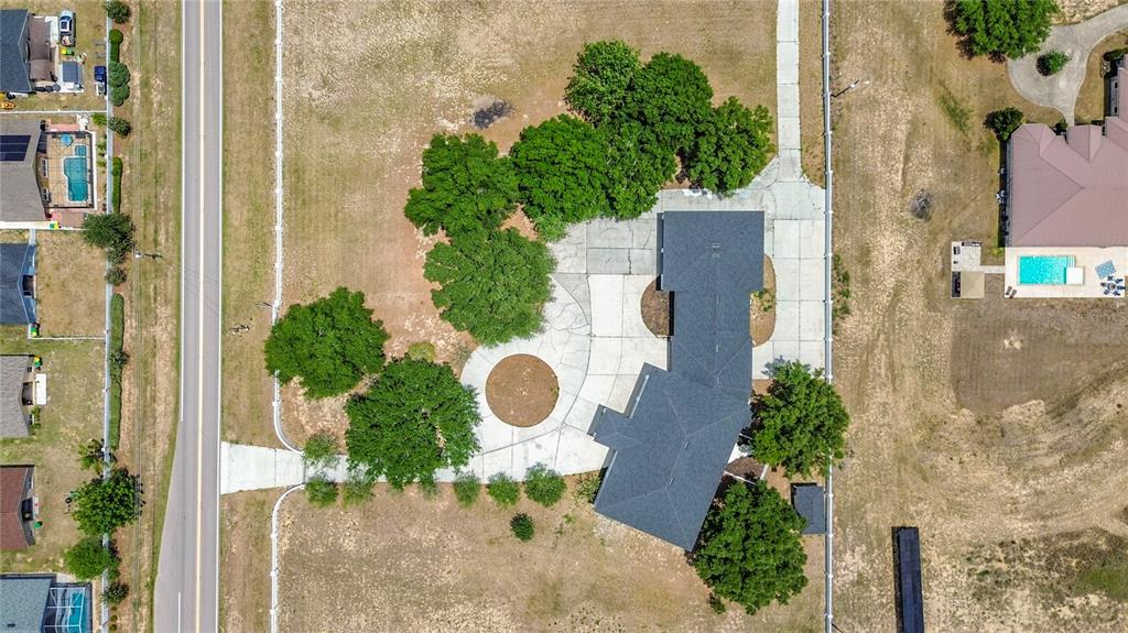 An aerial view shows a house with a large driveway, mature trees, and a swimming pool — 7925 LAKE MABEL LOOP ROAD, DUNDEE, FL