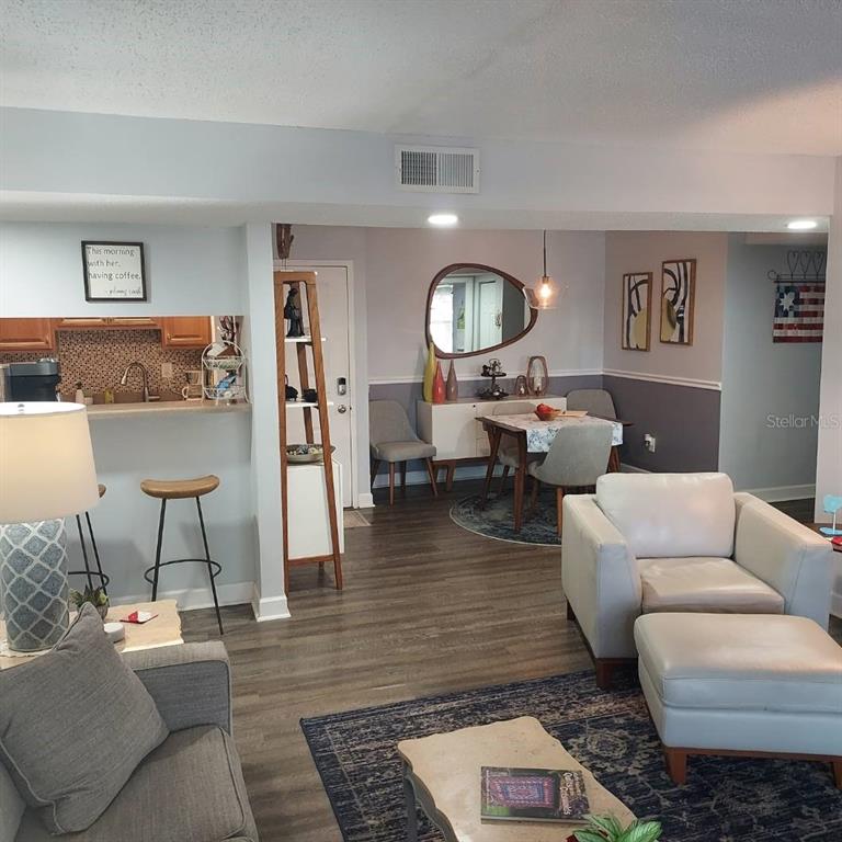 An open-concept living and dining area features wood-look flooring, a breakfast bar, and neutral walls — 4411 SHADY TERRACE LANE UNIT 209, TAMPA, FL