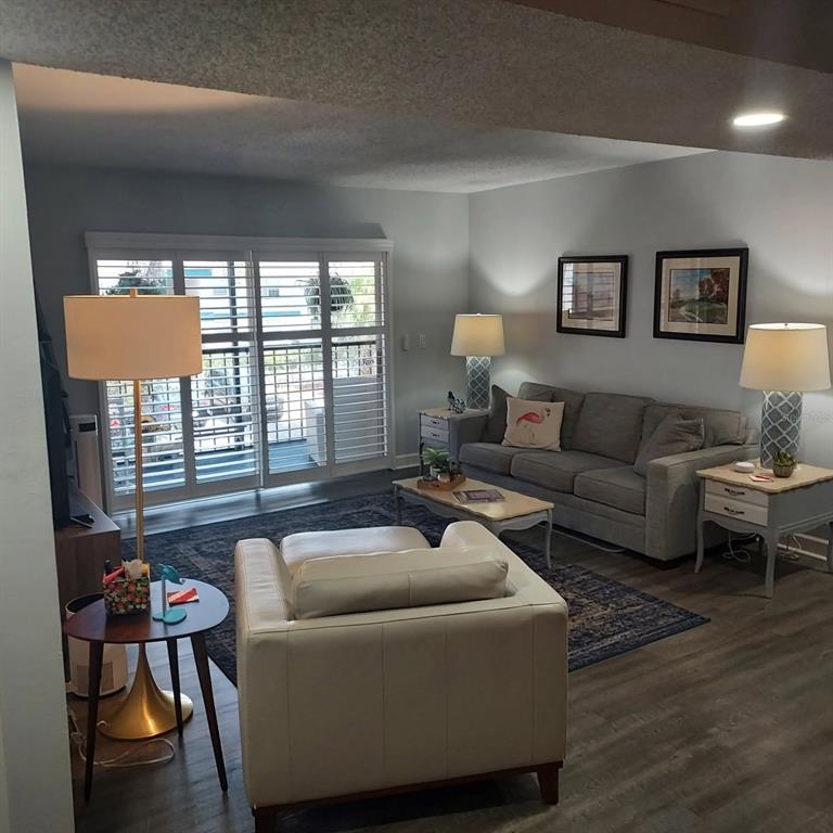 A living room features a grey sofa, a white armchair, and sliding glass doors with shutters — 4411 SHADY TERRACE LANE UNIT 209, TAMPA, FL