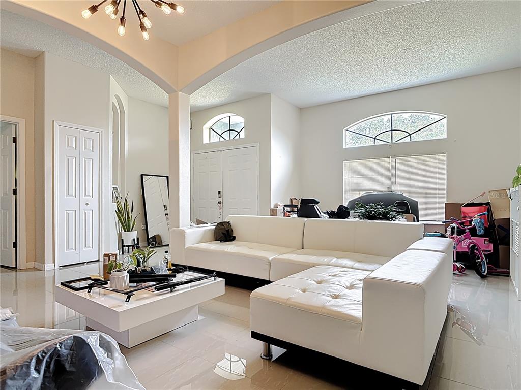 A bright living room features a white sectional sofa, a modern coffee table, and tile flooring — 1610 HANOVER AVENUE, DELTONA, FL