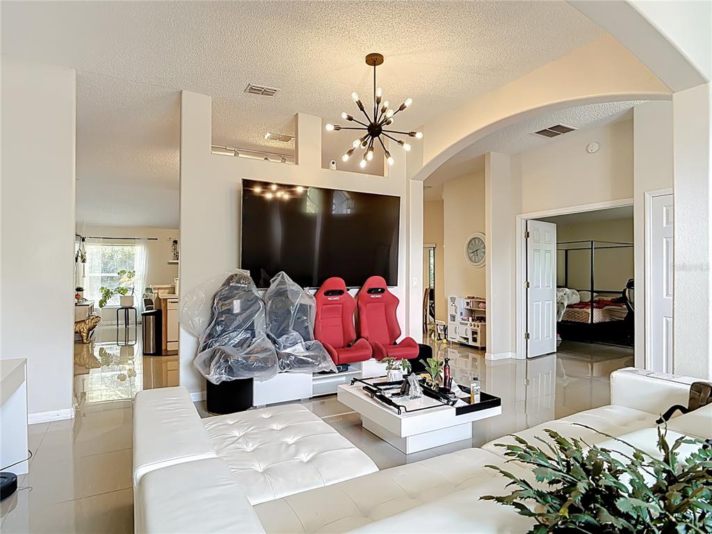 A living room features white leather sofas, red racing-style seats, and a modern sputnik chandelier — 1610 HANOVER AVENUE, DELTONA, FL