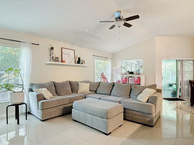 A living room features a large gray sectional sofa, an ottoman, and tile flooring — 1610 HANOVER AVENUE, DELTONA, FL