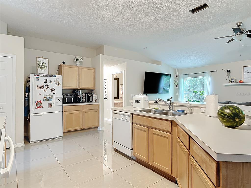 A kitchen with light wood cabinets, white appliances, and a peninsula counter with a sink — 1610 HANOVER AVENUE, DELTONA, FL