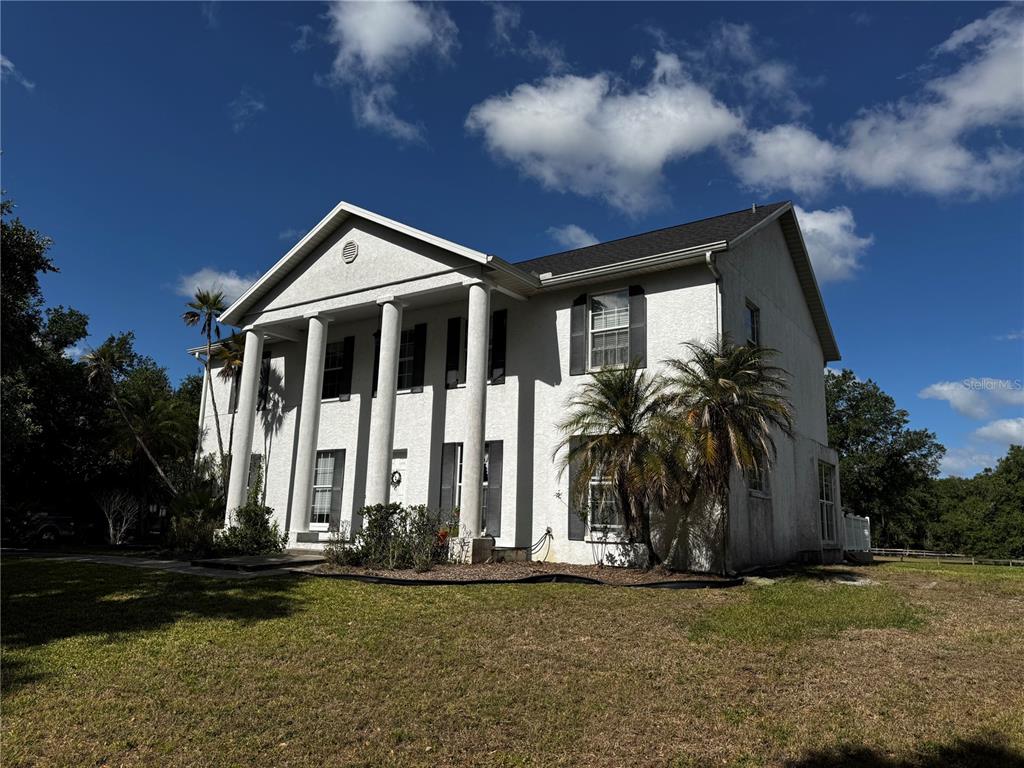 A two-story white house with a columned front porch and a triangular gable roof — 1701 BERN CREEK LOOP, SARASOTA, FL