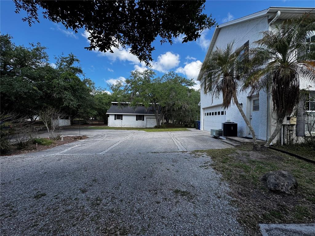 A gravel driveway leads to a white house with a garage and a detached building — 1701 BERN CREEK LOOP, SARASOTA, FL