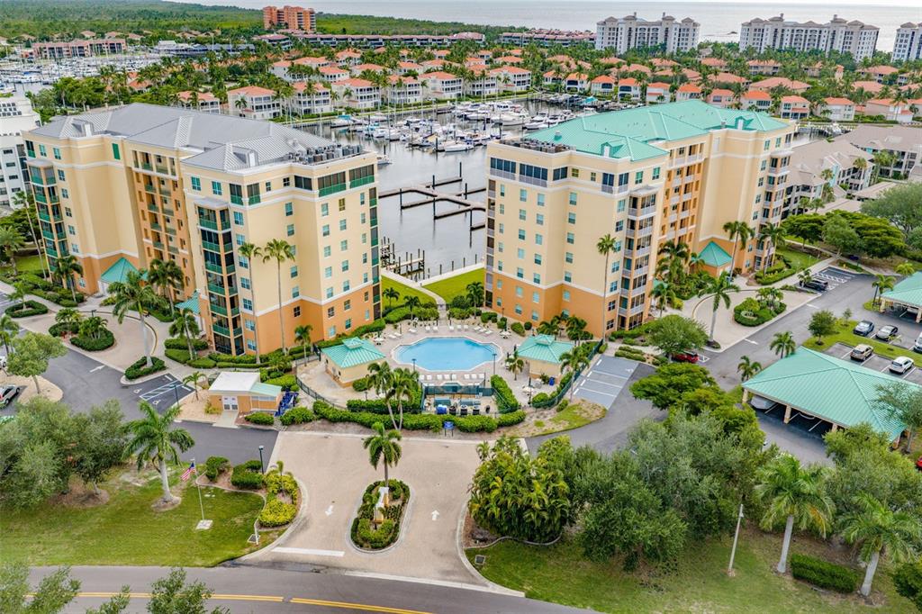 An aerial view shows two large residential buildings flanking a swimming pool and boat marina — 2060 MATECUMBE KEY ROAD UNIT 2803, PUNTA GORDA, FL