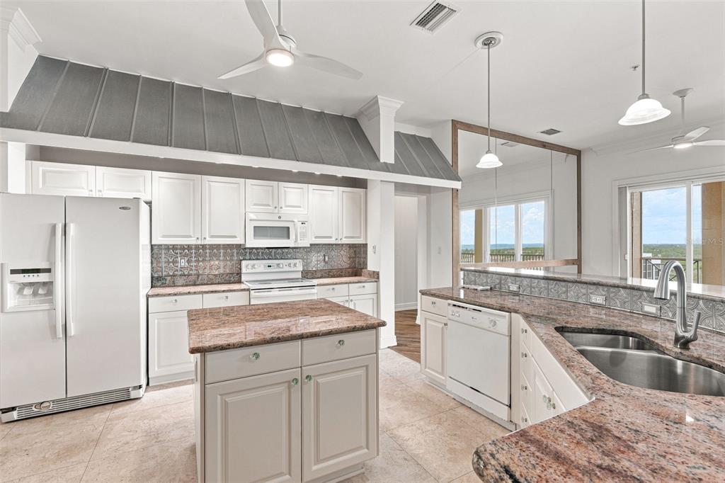 A kitchen features white cabinets, granite countertops, a center island, and a metal range hood — 2060 MATECUMBE KEY ROAD UNIT 2803, PUNTA GORDA, FL