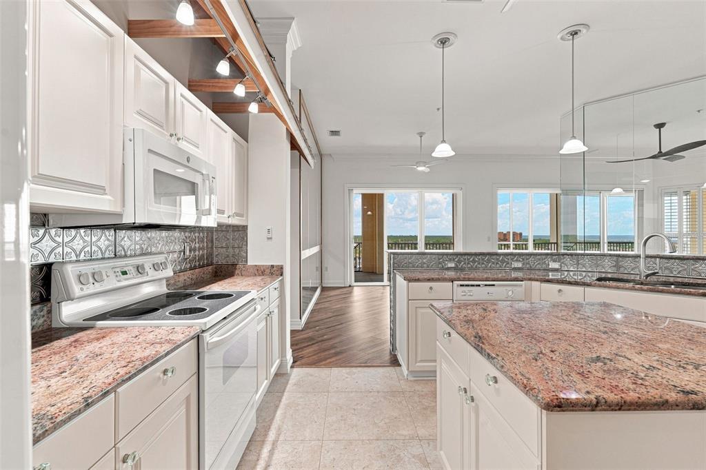 A kitchen with white cabinets, granite countertops, a center island, and a view of outdoors — 2060 MATECUMBE KEY ROAD UNIT 2803, PUNTA GORDA, FL