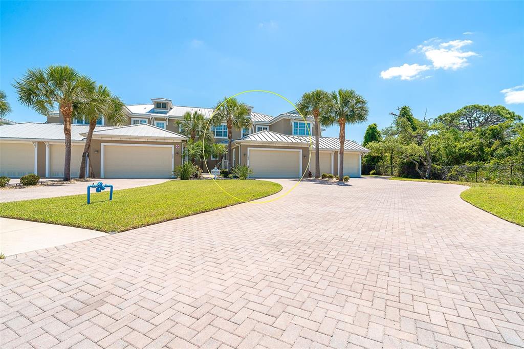 A multi-story residential building with attached garages and a paved driveway under a blue sky — 10700 LEMON CREEK LOOP UNIT 103, ENGLEWOOD, FL