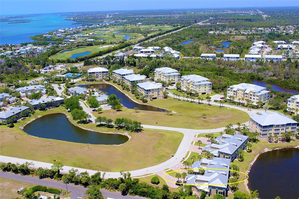 An aerial view shows a multi-story residential complex with ponds, landscaping, and a circled building — 10700 LEMON CREEK LOOP UNIT 103, ENGLEWOOD, FL