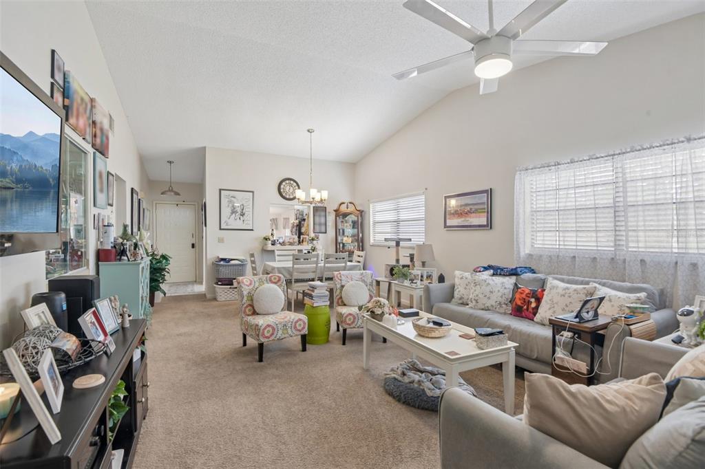A living room with carpeted floors, a ceiling fan, and a dining area in back — 8626 SHADBLOW COURT UNIT 1, PORT RICHEY, FL