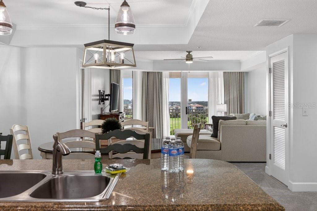 A kitchen island with a double sink overlooks a dining area and a living room — 200 OCEAN CREST DRIVE UNIT 517, PALM COAST, FL