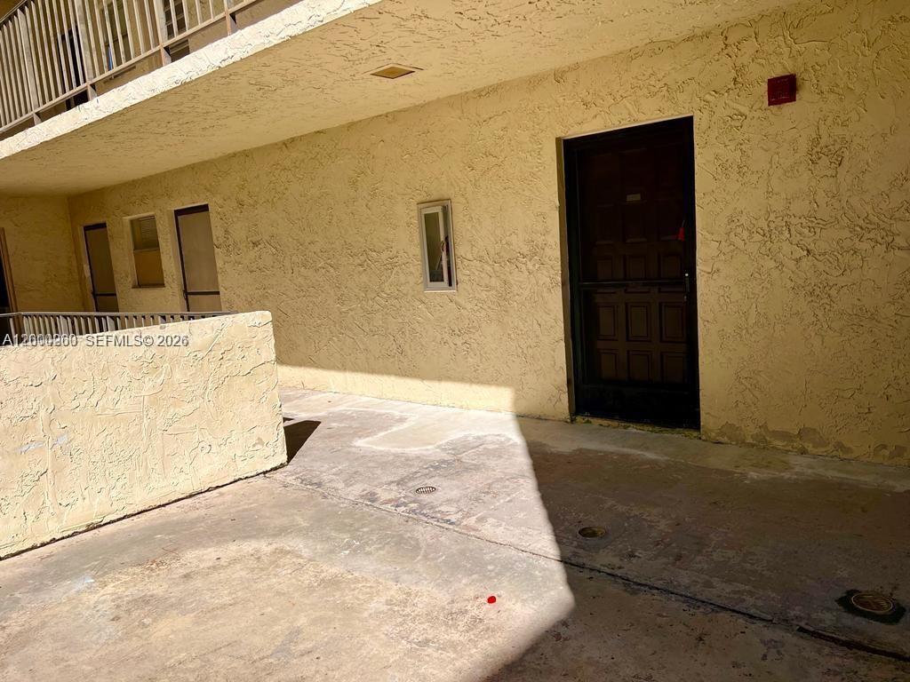 An exterior view of a building entrance with a dark door and textured walls — 3300 Spanish Moss Ter # 206, Lauderhill FL 33319, LAUDERHILL, FL