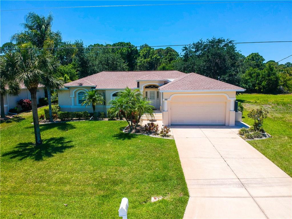 A single-story house with a beige exterior, a two-car garage, and a palm-lined front lawn — 155 LONG MEADOW LANE, ROTONDA WEST, FL