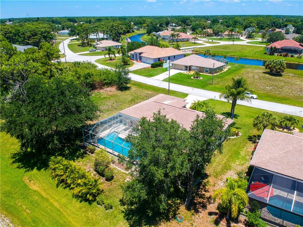 An aerial view of a suburban house with a screened-in pool and surrounding landscape — 155 LONG MEADOW LANE, ROTONDA WEST, FL