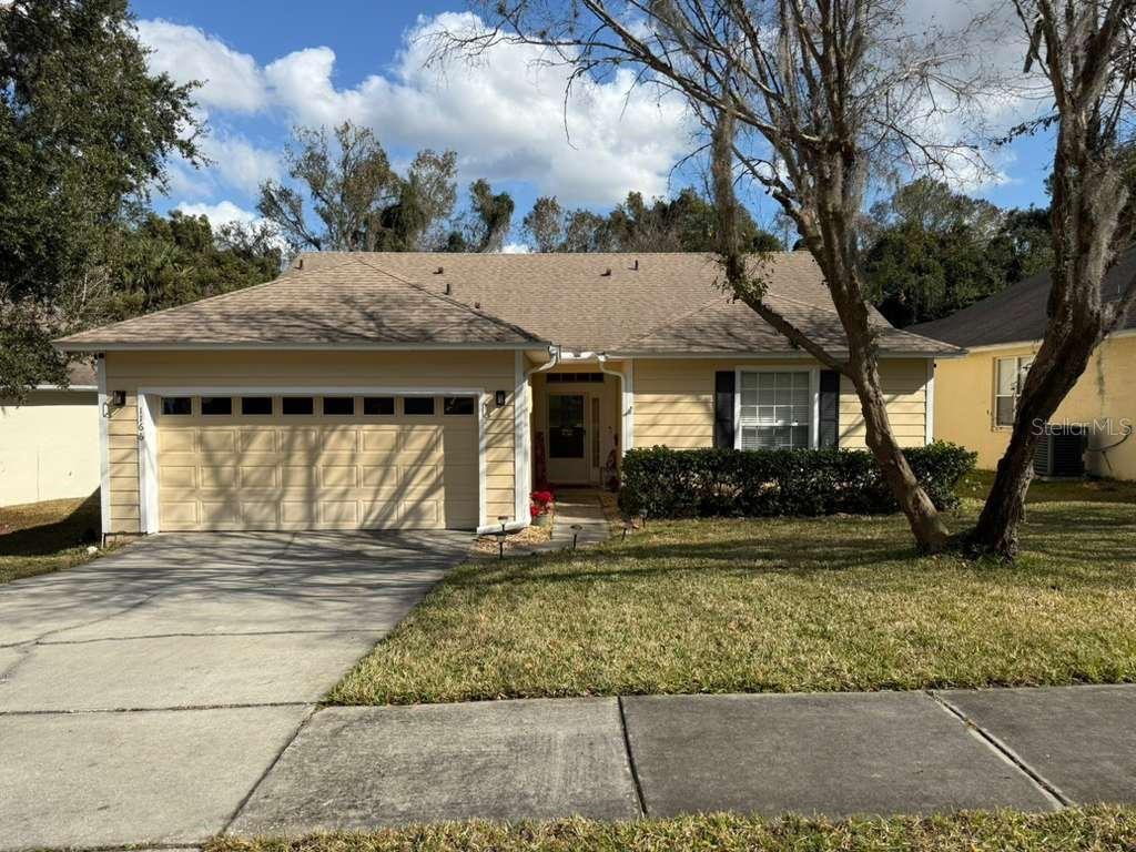A single-story house with yellow siding, a two-car garage, and a front lawn — 1166 DEKLEVA DRIVE, APOPKA, FL