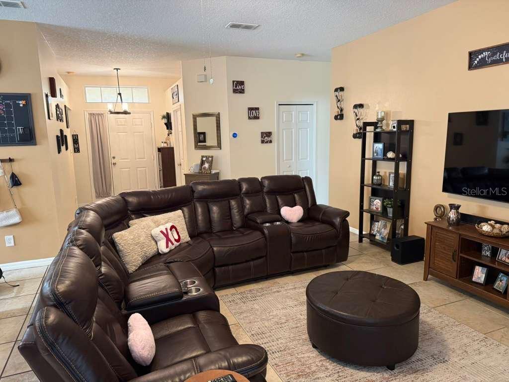 A living room features a large brown leather sectional, a matching ottoman, and a television — 1166 DEKLEVA DRIVE, APOPKA, FL