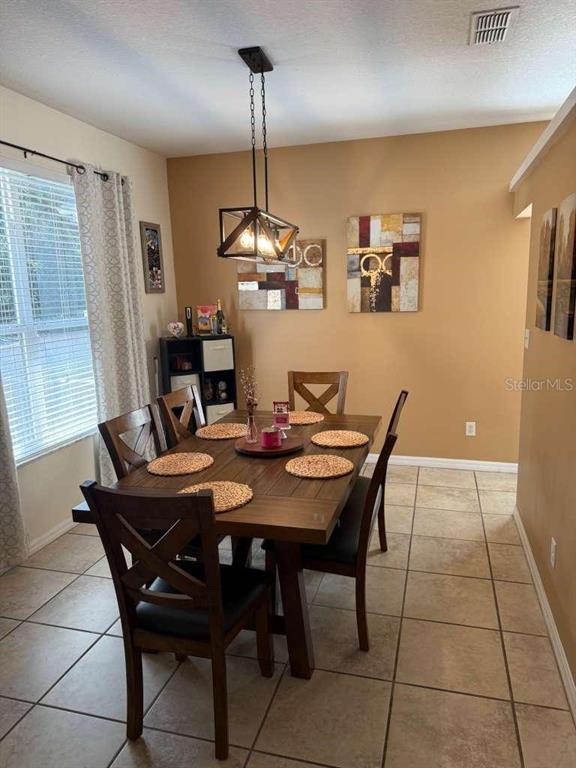 A dining room features a wooden table, six chairs, a pendant light, and tile flooring — 1166 DEKLEVA DRIVE, APOPKA, FL