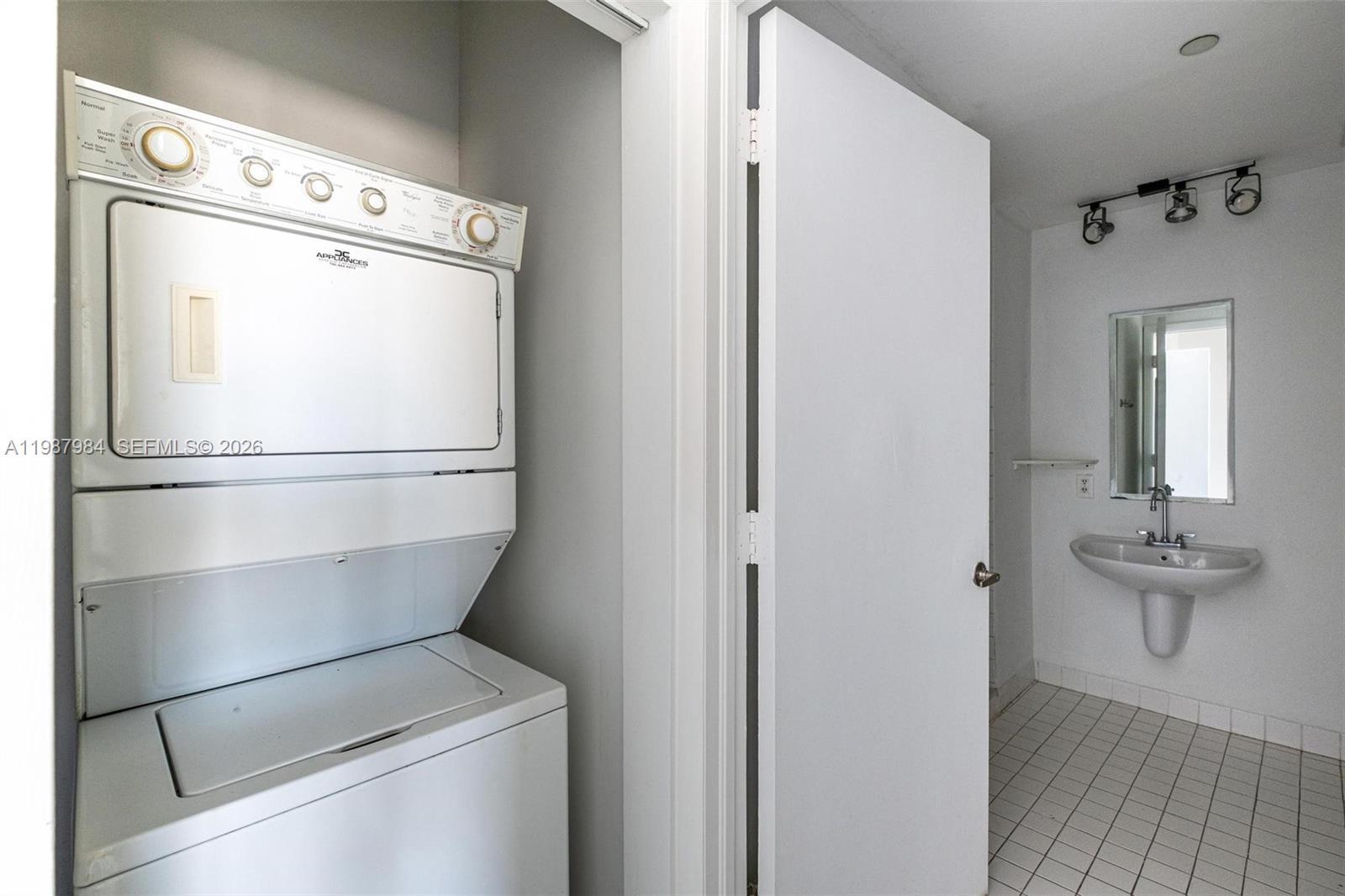 A stacked laundry unit sits in a closet next to a bathroom with a pedestal sink — 10 SW South River Dr # 609, Miami FL 33130, MIAMI, FL