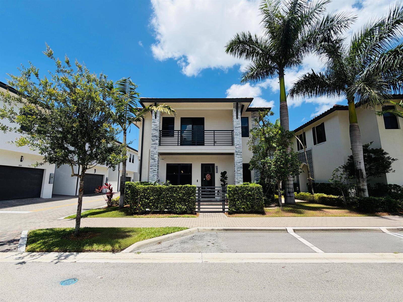 A two-story house with a balcony, stone accents, and a front hedge under a blue sky — 8288 NW 44th Terrace, Doral FL 33166, DORAL, FL