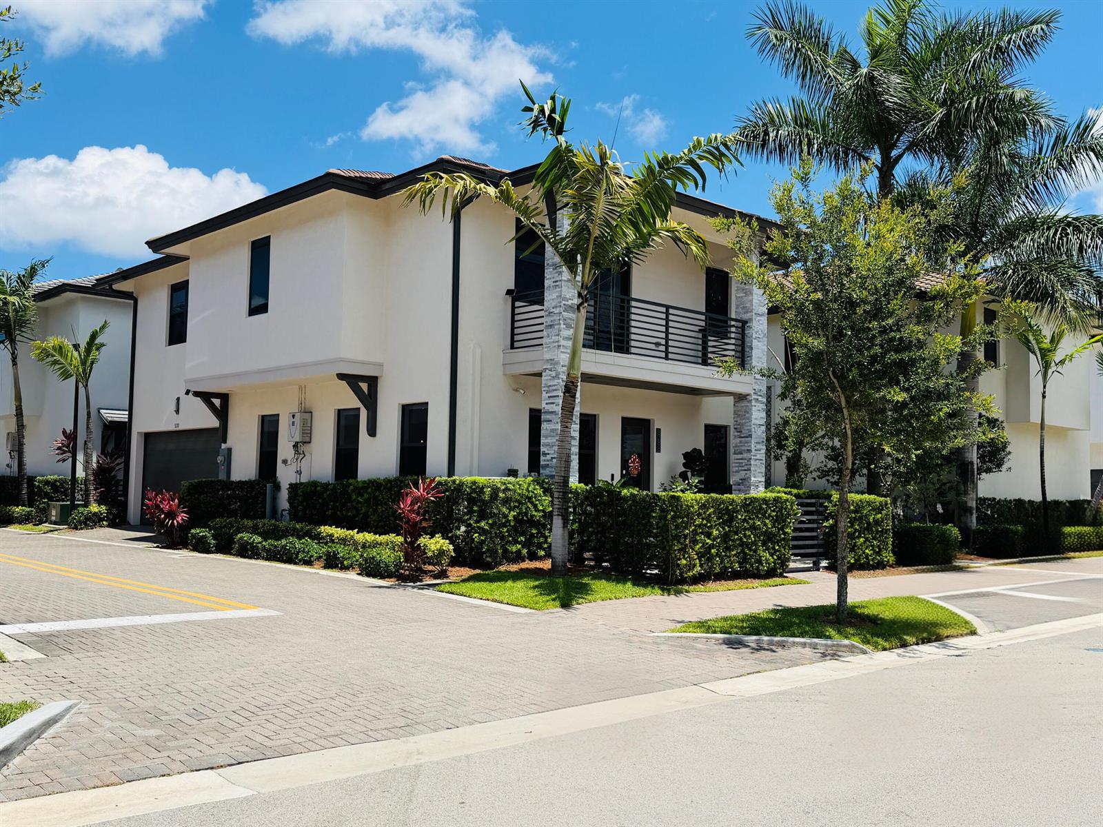 A two-story stucco townhouse with a balcony, stone columns, and manicured hedges — 8288 NW 44th Terrace, Doral FL 33166, DORAL, FL