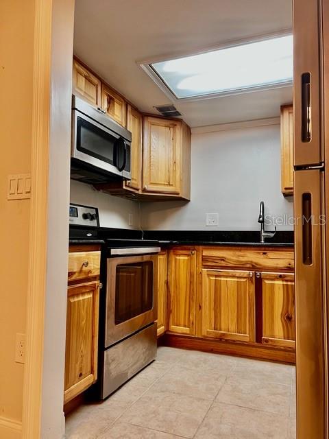 A kitchen features natural wood cabinets, stainless steel appliances, and a skylight — 942 LAKE DESTINY ROAD UNIT A, ALTAMONTE SPRINGS, FL