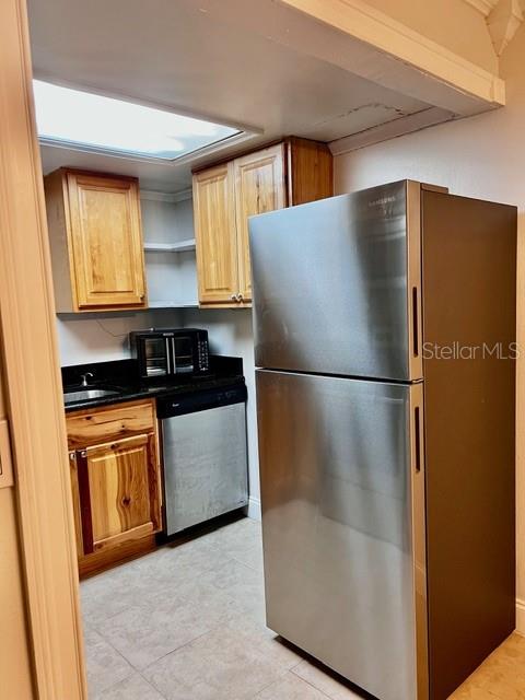 A kitchen features wooden cabinets, a stainless steel refrigerator, and a dishwasher — 942 LAKE DESTINY ROAD UNIT A, ALTAMONTE SPRINGS, FL