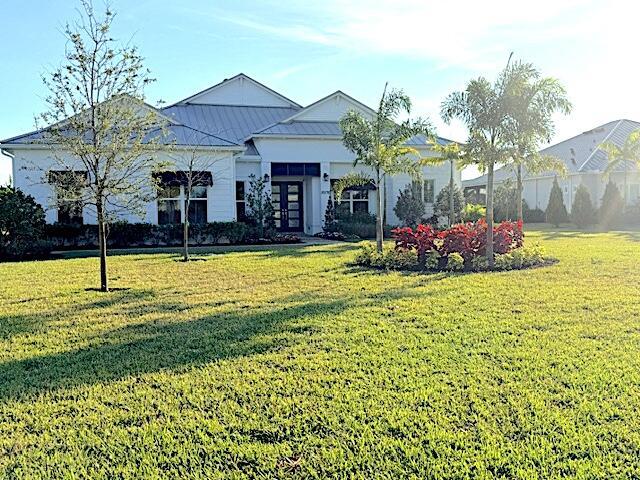 A white single-story house with a metal roof sits behind a large green lawn — 20076 SE Bridgewater Drive, Jupiter FL 33458, JUPITER, FL
