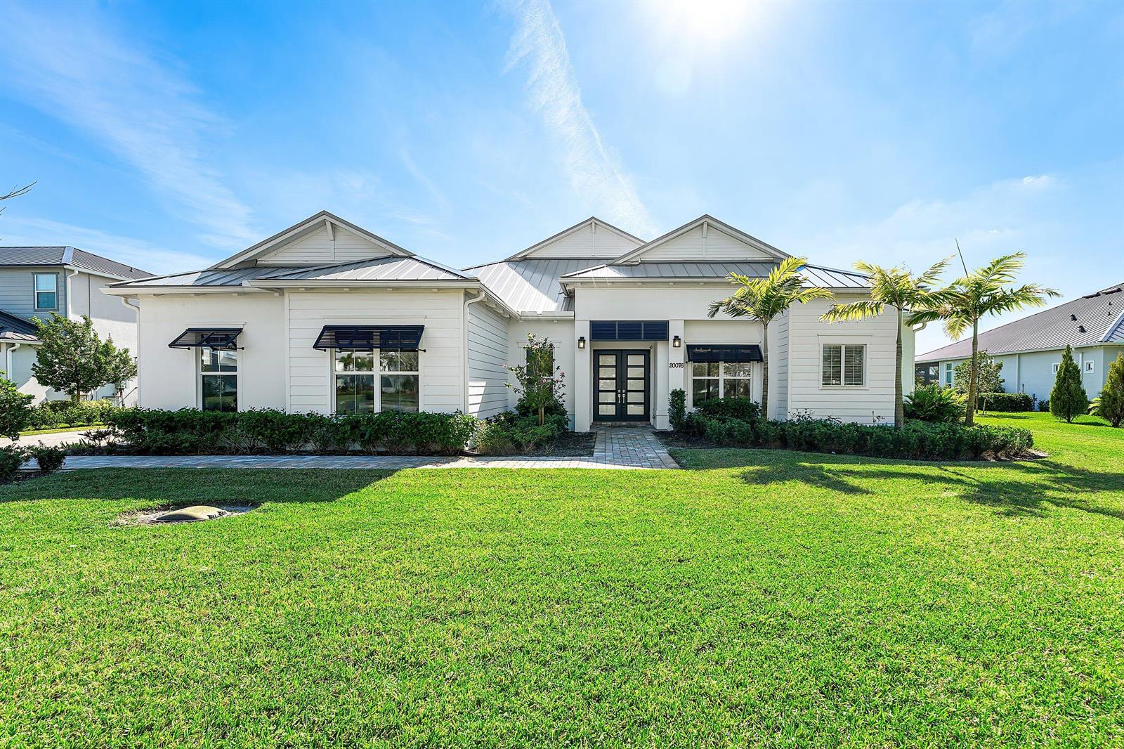 A white single-story house with a metal roof and a large front lawn — 20076 SE Bridgewater Drive, Jupiter FL 33458, JUPITER, FL