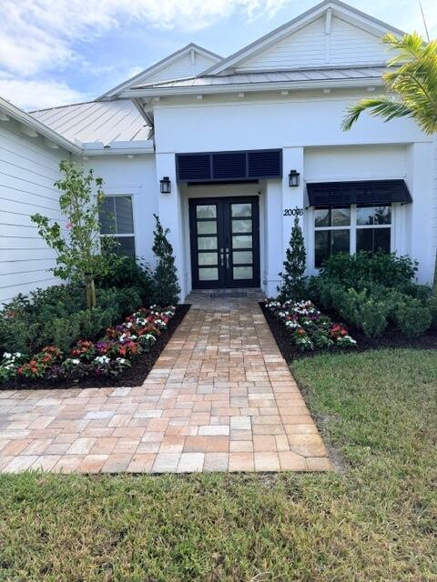 A paved walkway leads to the double front doors of a white house with landscaping — 20076 SE Bridgewater Drive, Jupiter FL 33458, JUPITER, FL
