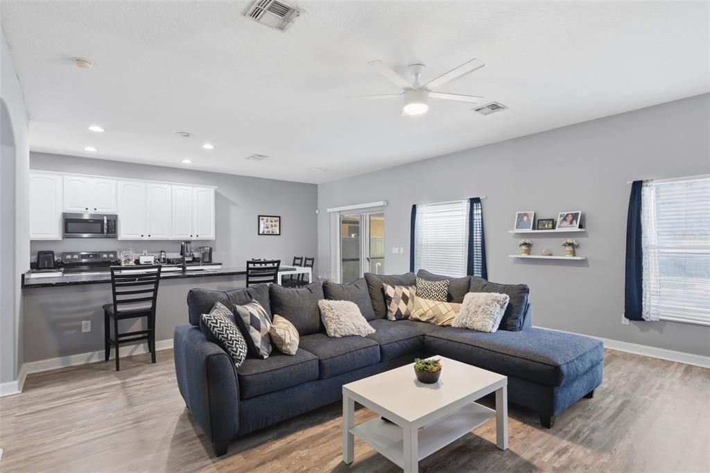 A living room with a dark blue sectional sofa, white coffee table, and open kitchen — 18124 SAXONY LANE, ORLANDO, FL