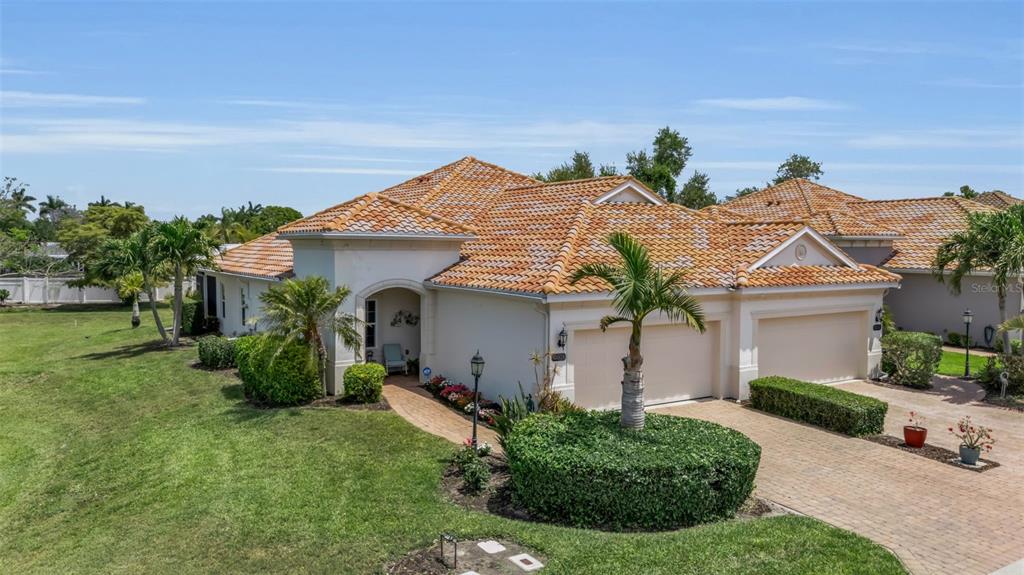 An exterior view of a single-story house with a tiled roof and a paved driveway — 7004 VISTA BELLA DRIVE, BRADENTON, FL