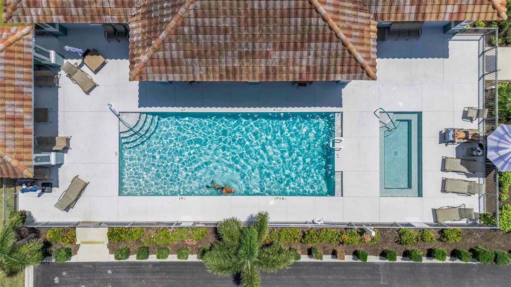 An aerial view shows a rectangular swimming pool and spa surrounded by a concrete deck — 7004 VISTA BELLA DRIVE, BRADENTON, FL