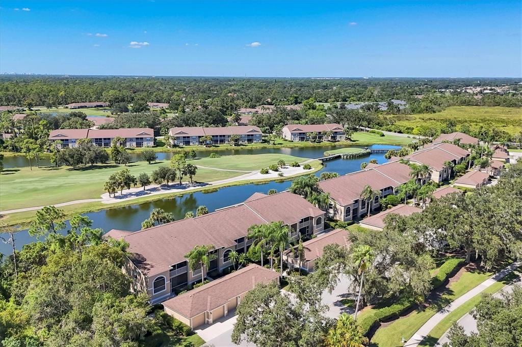 An aerial view shows multi-story apartment buildings situated along a golf course and pond — 5240 HYLAND HILLS AVENUE UNIT 1426, SARASOTA, FL