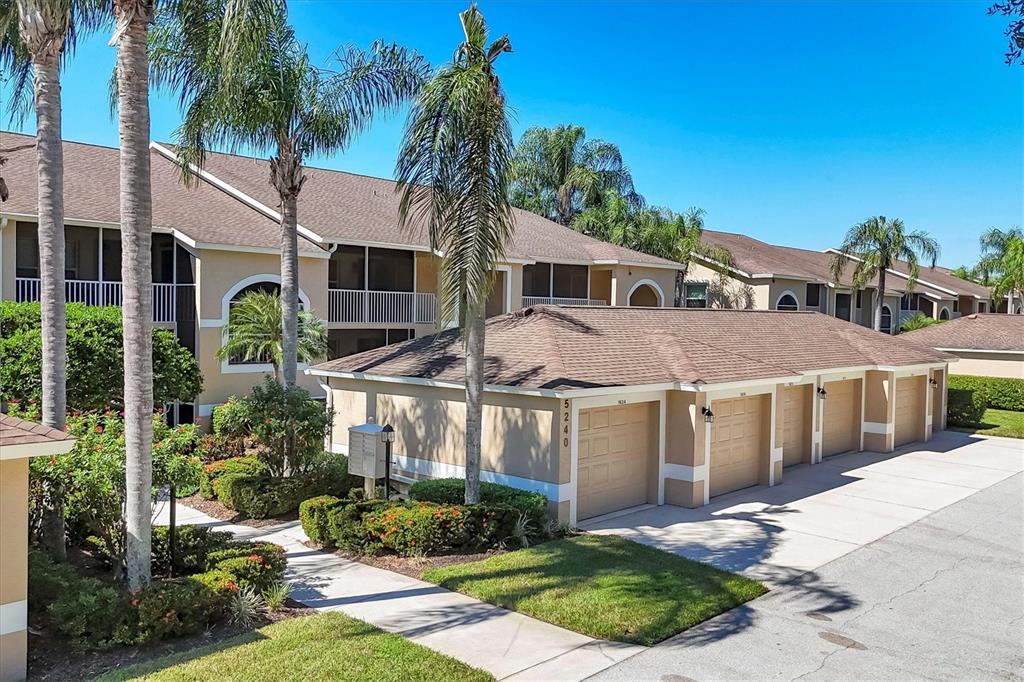 An exterior view of a multi-story apartment building with a row of attached garages — 5240 HYLAND HILLS AVENUE UNIT 1426, SARASOTA, FL