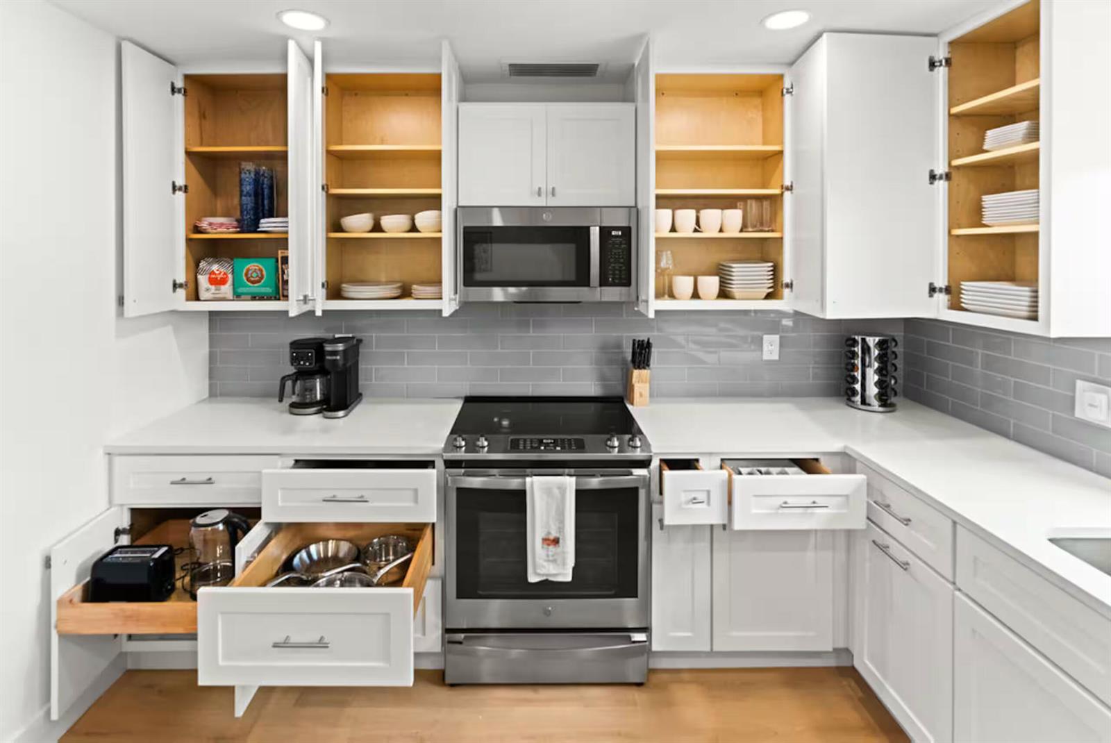 A modern kitchen features white cabinets, stainless steel appliances, and gray subway tile backsplashes — 1216 Surf Road, Singer Island FL 33404, SINGER ISLAND, FL