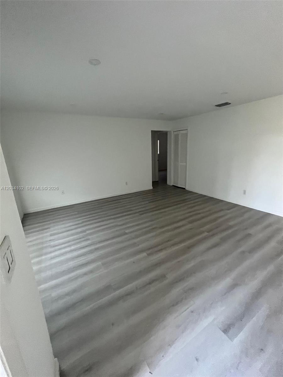 An empty room features light gray wood-look flooring and white walls — 1402 SE 34th ST # 0, Cape Coral FL 33904, CAPE CORAL, FL