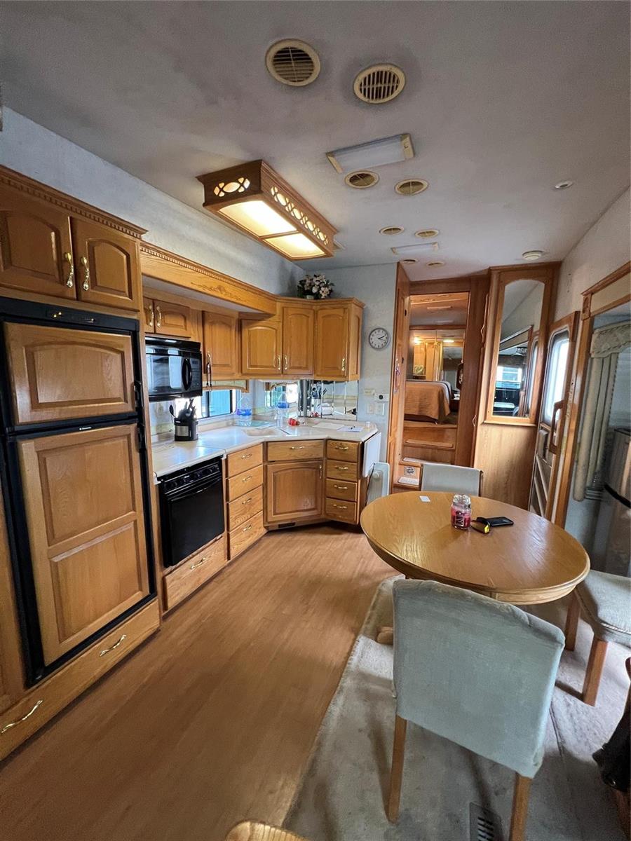 A kitchen and dining area in an RV featuring wood cabinetry and a round table — 5355 SE 64th Terrace, Okeechobee FL 34974, OKEECHOBEE, FL