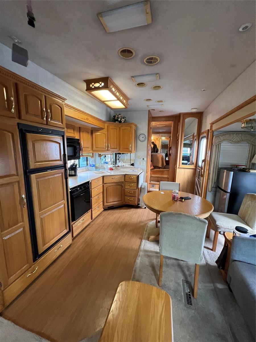 A kitchen and dining area in an RV featuring wood cabinetry and light-colored flooring — 5355 SE 64th Terrace, Okeechobee FL 34974, OKEECHOBEE, FL