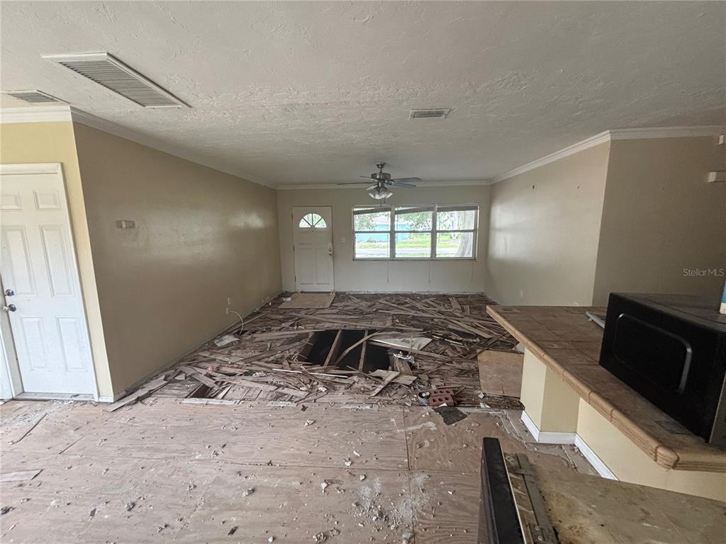 A living room with a large hole in the subfloor and exposed wooden joists — 5620 2ND AVENUE DRIVE W, BRADENTON, FL